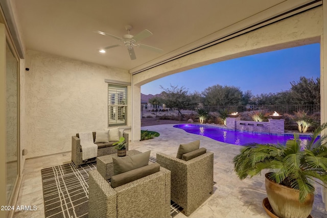 pool at dusk with a patio area, ceiling fan, pool water feature, and an outdoor hangout area