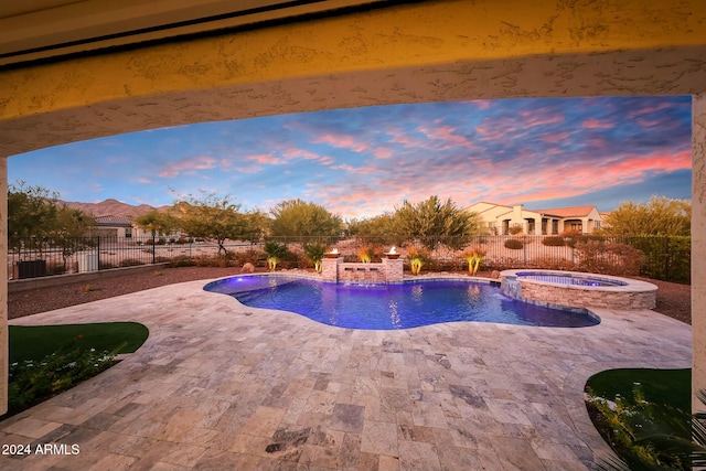 pool at dusk with pool water feature, an in ground hot tub, and a patio