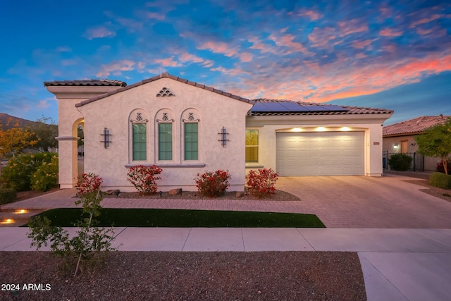 20594 W Pasadena Ave, Buckeye, AZ 85396 - mediterranean / spanish-style home featuring driveway, roof mounted solar panels, stucco siding, a garage, and a tile roof