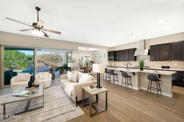 living room featuring ceiling fan, sink, and light hardwood / wood-style flooring