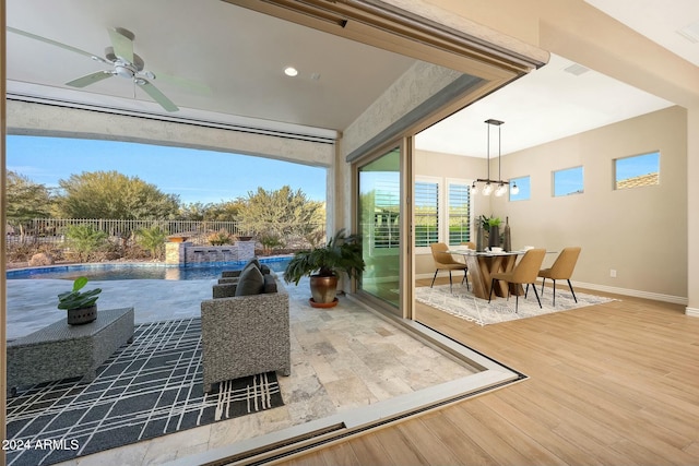 sunroom featuring ceiling fan with notable chandelier