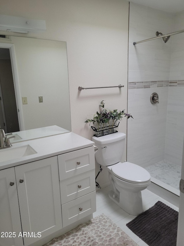 bathroom featuring vanity, tile patterned flooring, toilet, and tiled shower