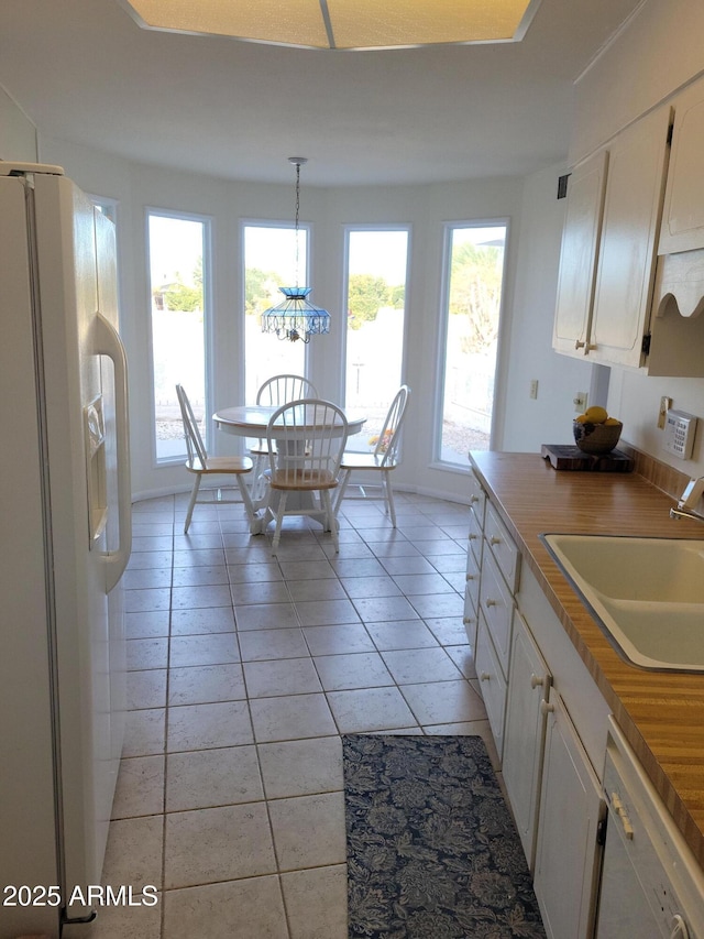 kitchen featuring sink, light tile patterned floors, pendant lighting, white appliances, and a healthy amount of sunlight