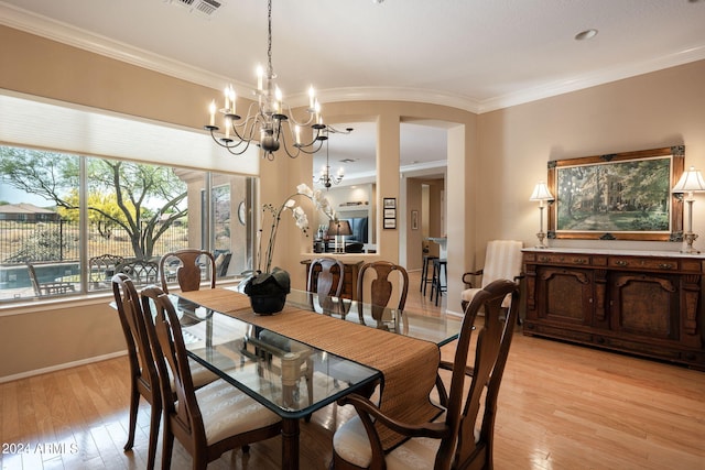 dining room featuring ornamental molding, light hardwood / wood-style flooring, and a notable chandelier