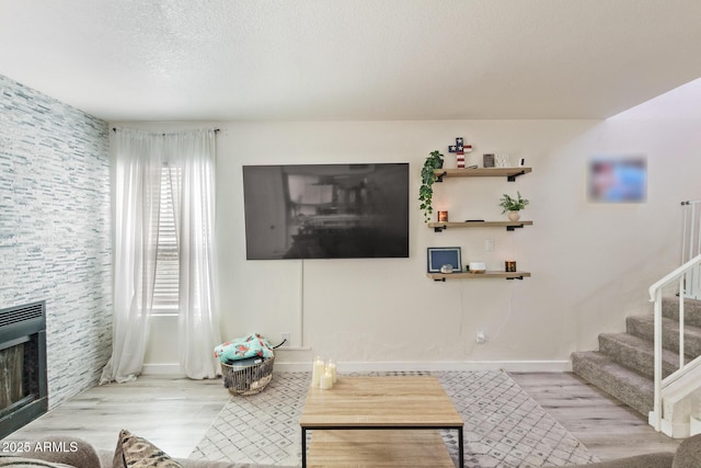 living room featuring a fireplace, a textured ceiling, and light hardwood / wood-style floors