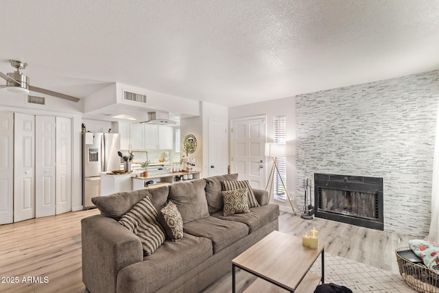 living room featuring a fireplace, light hardwood / wood-style flooring, and a textured ceiling