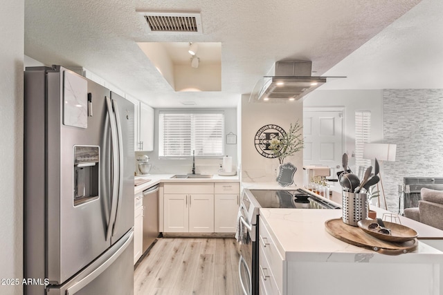 kitchen with sink, a textured ceiling, light hardwood / wood-style floors, white cabinetry, and stainless steel appliances