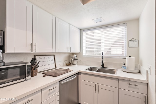 kitchen featuring sink, white cabinets, a textured ceiling, and appliances with stainless steel finishes