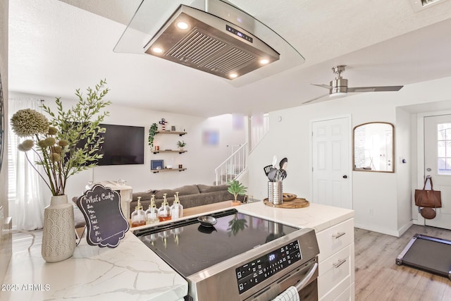 kitchen featuring white cabinetry, ceiling fan, light stone countertops, stainless steel range oven, and light hardwood / wood-style floors