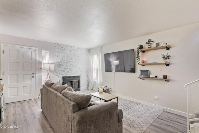 living room featuring a stone fireplace, a wealth of natural light, and light wood-type flooring