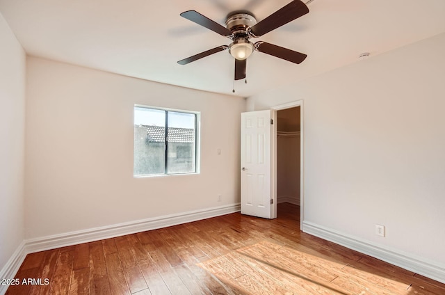 unfurnished bedroom with ceiling fan, a closet, a spacious closet, and light hardwood / wood-style flooring