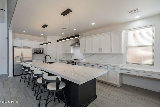 694 W Desert Seasons Dr, San Tan Valley, AZ 85143 - kitchen with appliances with stainless steel finishes, wall chimney exhaust hood, white cabinetry, light wood finished floors, and recessed lighting