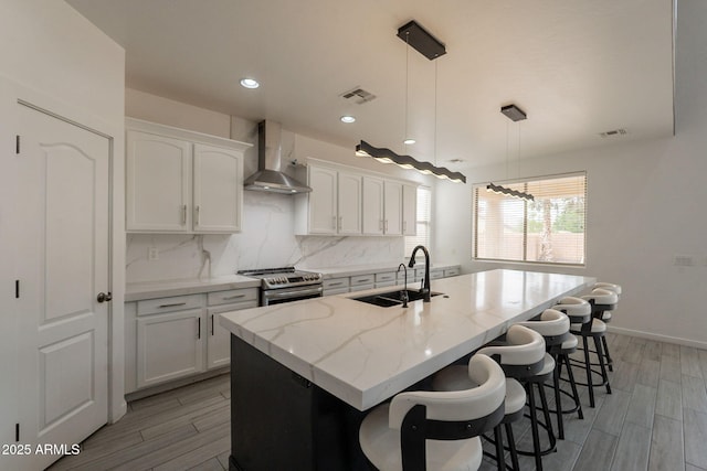 694 W Desert Seasons Dr, San Tan Valley, AZ 85143 - kitchen featuring wall chimney range hood, stainless steel electric stove, a center island with sink, tasteful backsplash, and white cabinetry