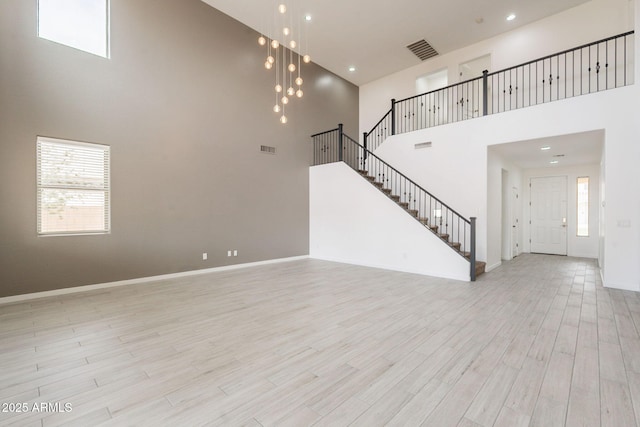 694 W Desert Seasons Dr, San Tan Valley, AZ 85143 - unfurnished living room with a high ceiling, stairs, light wood-style floors, healthy amount of natural light, and recessed lighting