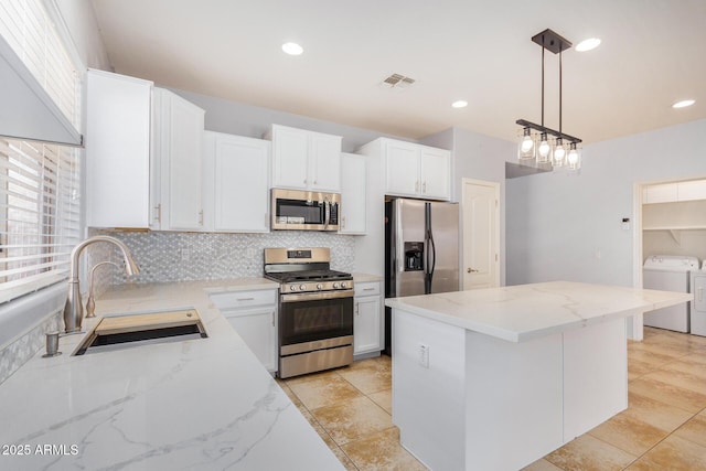 kitchen featuring washer and clothes dryer, visible vents, decorative backsplash, appliances with stainless steel finishes, and a sink