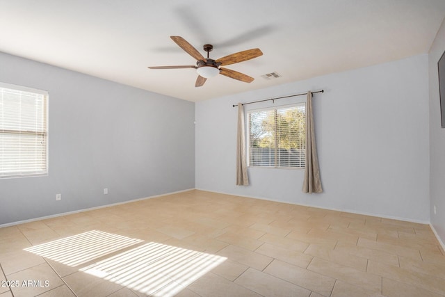 unfurnished room with ceiling fan, light tile patterned floors, visible vents, and baseboards