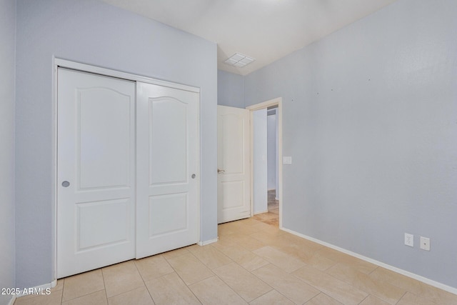 unfurnished bedroom featuring a closet, visible vents, baseboards, and light tile patterned floors