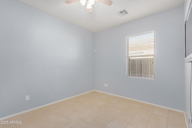 spare room featuring ceiling fan, visible vents, and baseboards