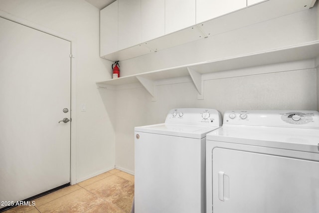 clothes washing area featuring cabinet space, light tile patterned floors, and washer and clothes dryer