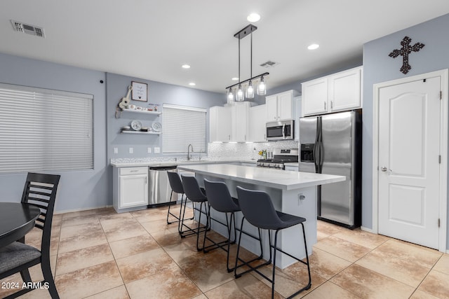 kitchen featuring appliances with stainless steel finishes, white cabinetry, sink, a kitchen island, and a breakfast bar