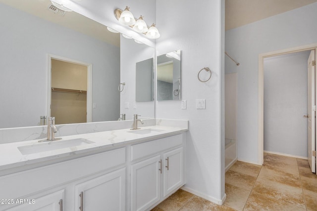 bathroom with double vanity, a sink, visible vents, and a walk in closet