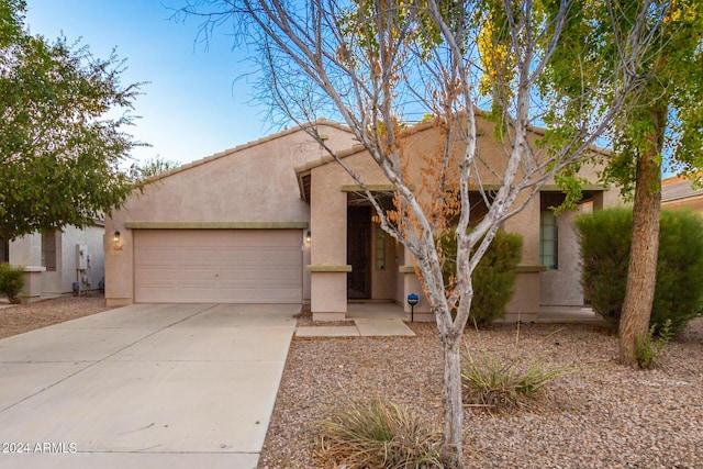 pueblo revival-style home with an attached garage, driveway, and stucco siding