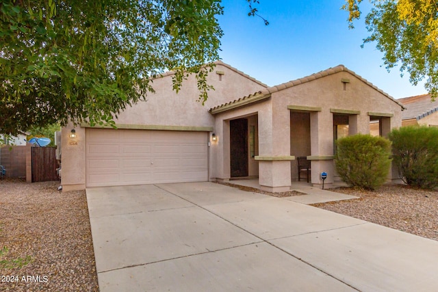 mediterranean / spanish home featuring an attached garage, fence, concrete driveway, and stucco siding