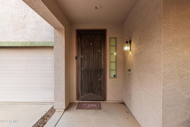 property entrance featuring a garage and stucco siding