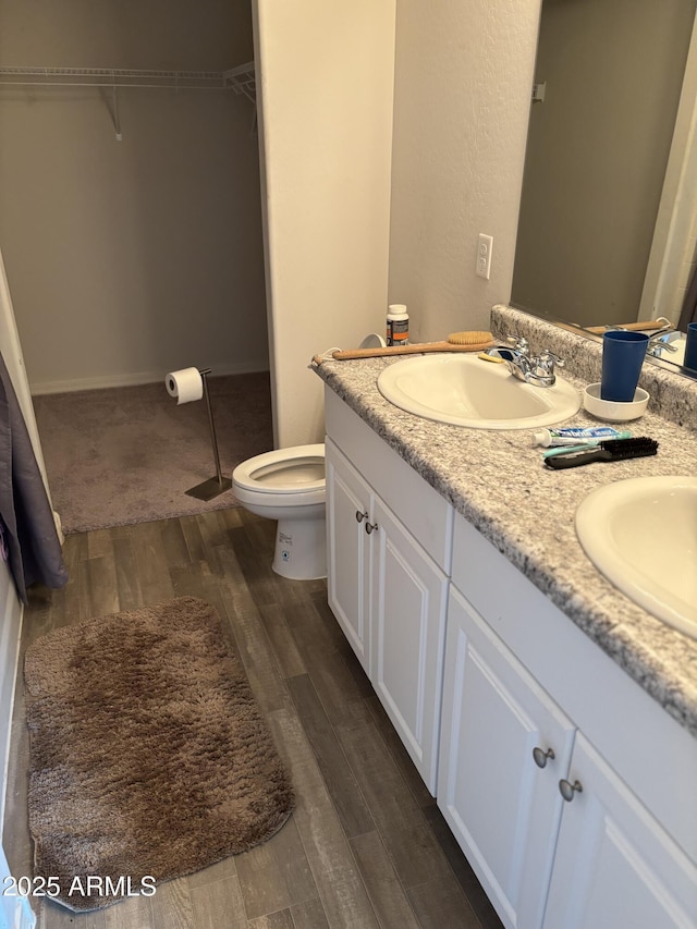 131 E Douglas Ave, Coolidge, AZ 85128 - bathroom featuring wood finished floors, double vanity, toilet, and a walk in closet