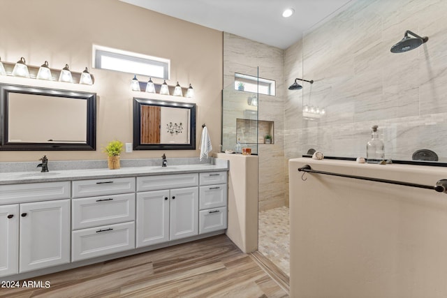 bathroom with hardwood / wood-style flooring, vanity, and a tile shower