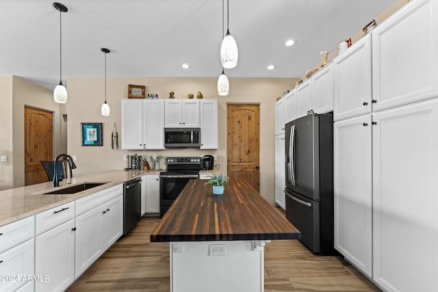 kitchen featuring stainless steel appliances, wooden counters, sink, light wood-type flooring, and a center island