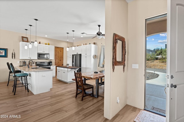 kitchen with pendant lighting, appliances with stainless steel finishes, white cabinetry, kitchen peninsula, and light wood-type flooring