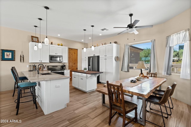 kitchen with pendant lighting, white cabinetry, sink, kitchen peninsula, and stainless steel appliances