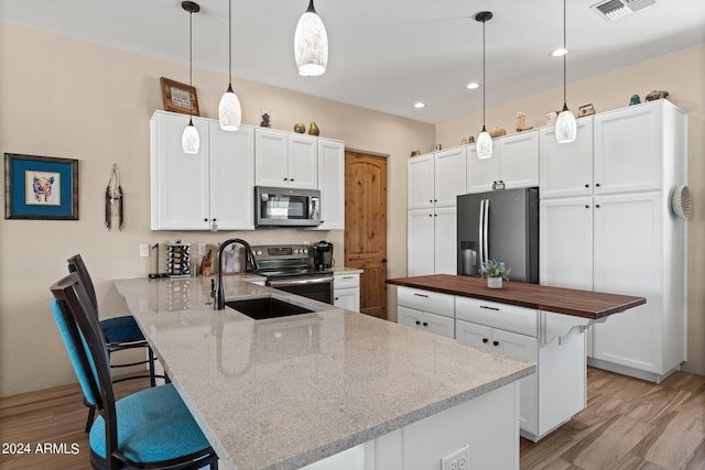 kitchen featuring white cabinets, a kitchen breakfast bar, hanging light fixtures, kitchen peninsula, and stainless steel appliances