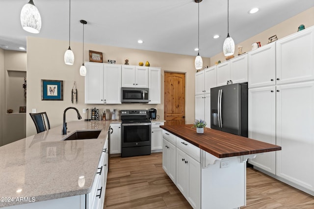 kitchen featuring pendant lighting, butcher block countertops, sink, appliances with stainless steel finishes, and white cabinets