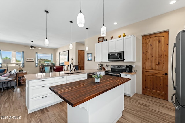 kitchen featuring sink, decorative light fixtures, stainless steel appliances, and wooden counters