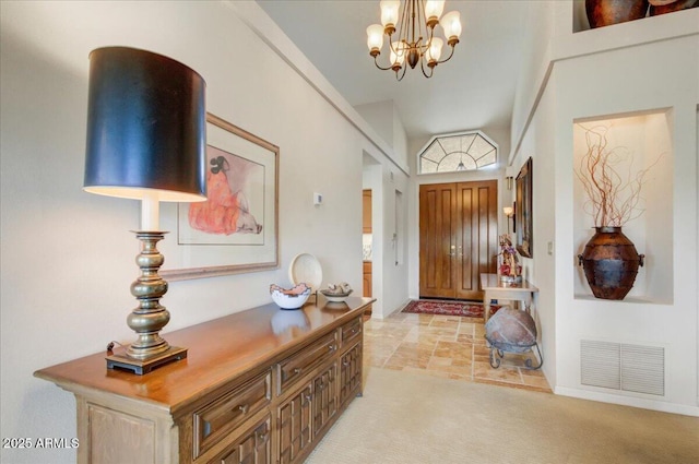 entryway with a notable chandelier, visible vents, light colored carpet, and baseboards