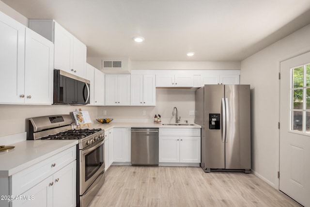 kitchen featuring recessed lighting, appliances with stainless steel finishes, a sink, white cabinetry, and visible vents