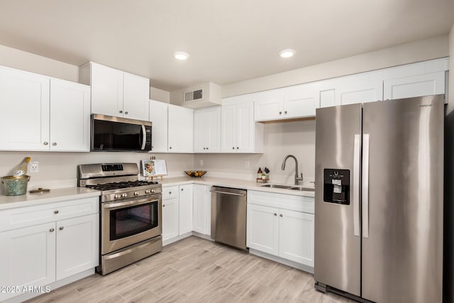 kitchen featuring a sink, stainless steel appliances, visible vents, light countertops, and white cabinets