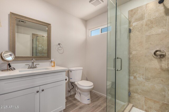 full bathroom with toilet, visible vents, a shower stall, and wood finished floors