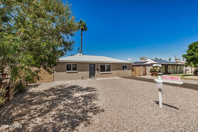 single story home featuring solar panels and fence