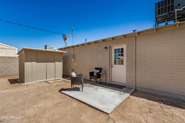 back of house with a storage unit, a patio area, stucco siding, an outbuilding, and fence