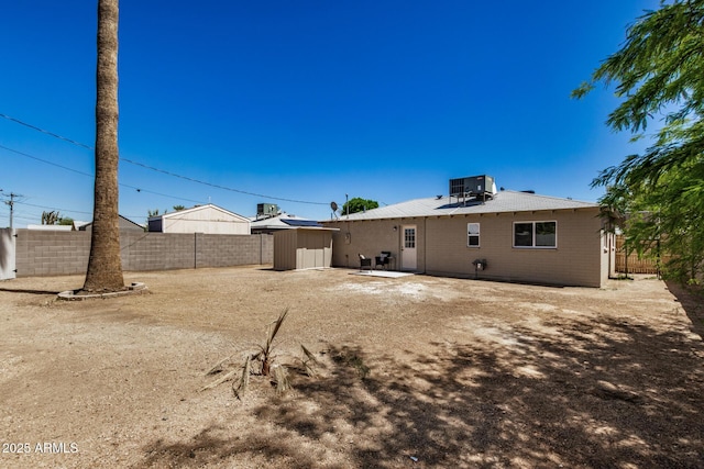 rear view of property with an outdoor structure, cooling unit, a storage unit, a patio area, and a fenced backyard