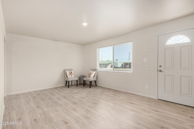 entryway featuring light wood finished floors and brick wall