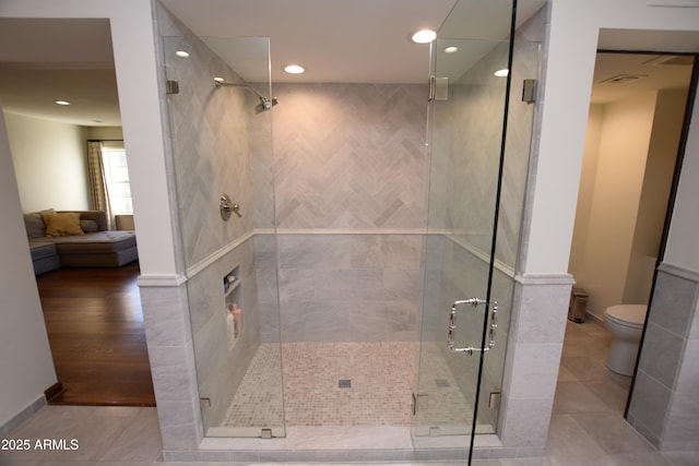 bathroom featuring a shower with door, tile patterned flooring, and toilet