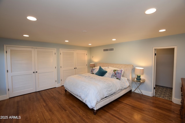 bedroom with dark hardwood / wood-style flooring and multiple closets