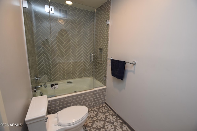 bathroom with tile patterned flooring, toilet, and combined bath / shower with glass door