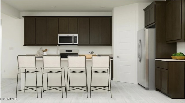 11946 W Calle De Pompas, Peoria, AZ 85383 - kitchen with stainless steel appliances, dark brown cabinets, a breakfast bar area, light countertops, and a center island