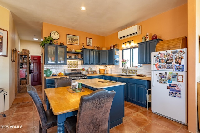 42617 Hovatter Rd, Salome, AZ 85348 - kitchen with blue cabinets, stainless steel gas range oven, freestanding refrigerator, a wall unit AC, and a sink