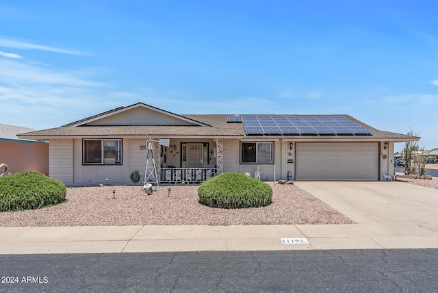 single story home with solar panels, a garage, and covered porch